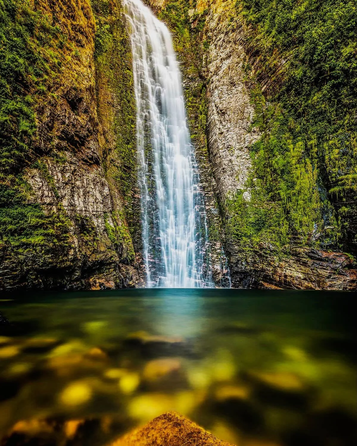 Cachoeira do Segredo caindo em paredão coberto de vegetação, com poço ao pé