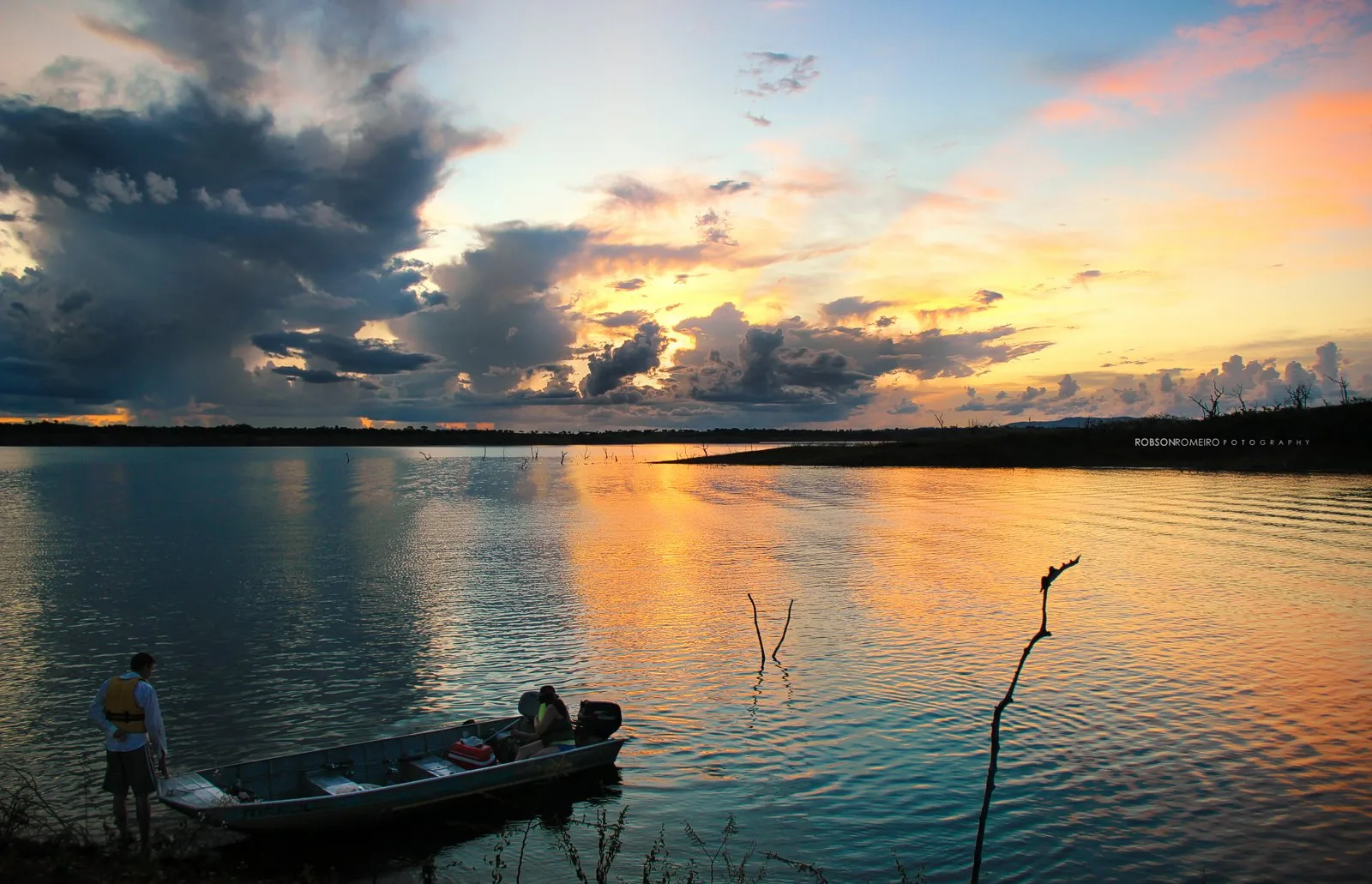 Pôr do sol sobre o Lago de Serra da Mesa, com um barco na margem